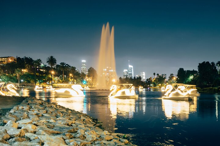 Glide across Echo Park Lake on illuminated swan boats surrounded by stunning city lights and a picturesque fountain creating memorable moments under the stars. A perfect outdoor escape!